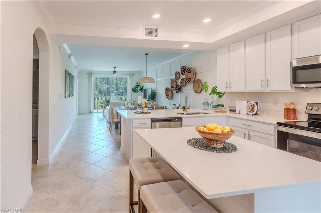 Kitchen featuring white cabinetry, stainless steel appliances, white countertops, a large island, and tile flooring