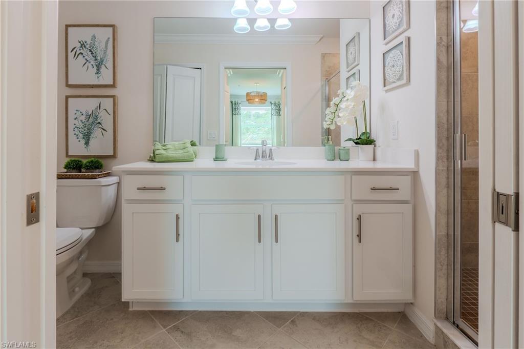 Bathroom featuring a single vanity with white cabinetry, a large mirror, and a glass-enclosed shower