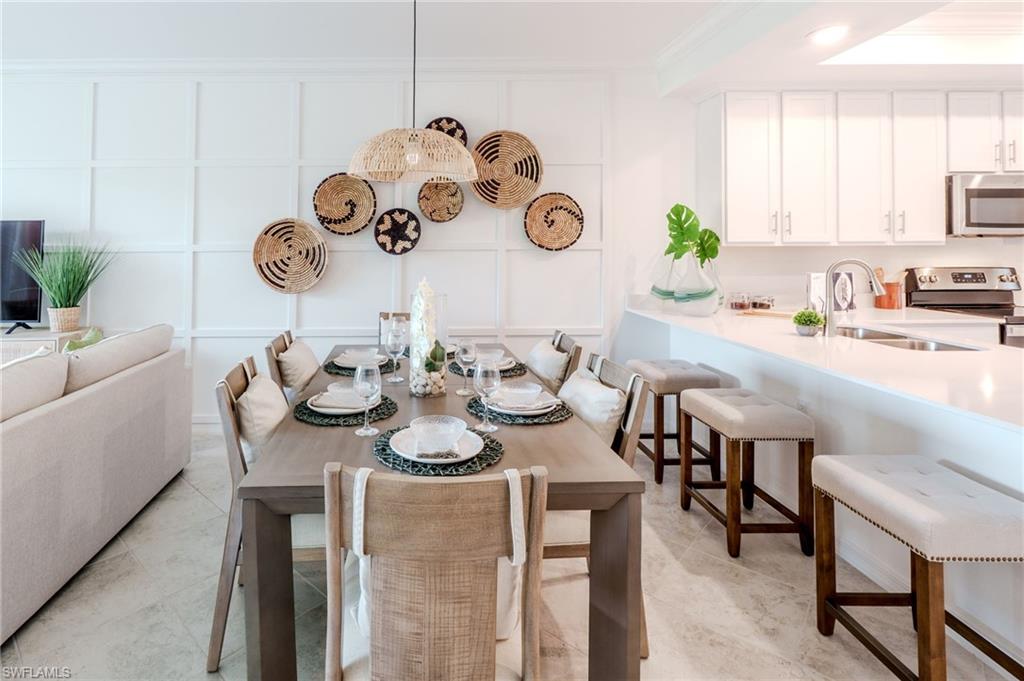 Open-concept living space featuring a dining area with a linear pendant light, white wainscoting, and wood-finish flooring
