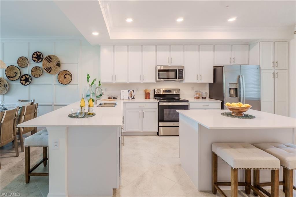 Kitchen featuring white cabinetry, stainless steel appliances, a double island with seating, and recessed lighting