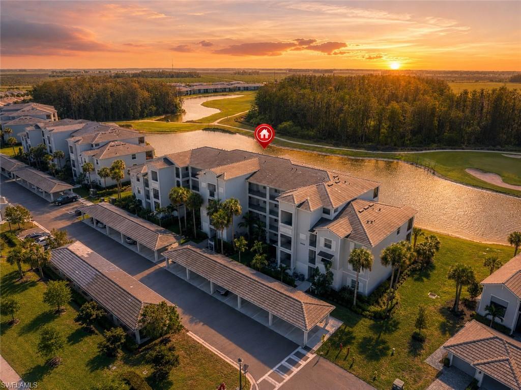 Waterfront condominium building with multiple balconies, covered parking structures, and manicured landscaping