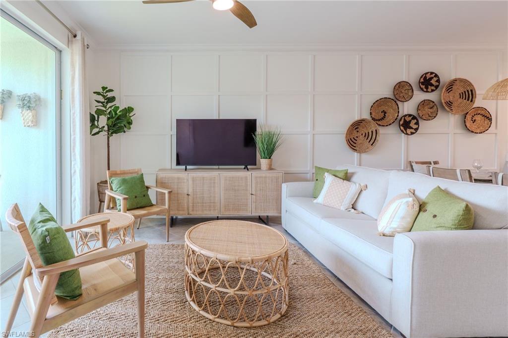 White wall paneling, large sliding glass door, ceiling fan with integrated lighting, wood-finish console