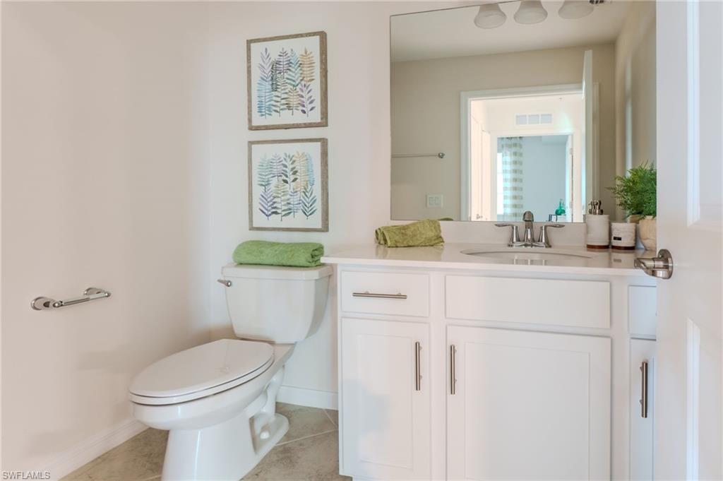 White vanity with a single basin, stainless steel faucet, and overhead lighting