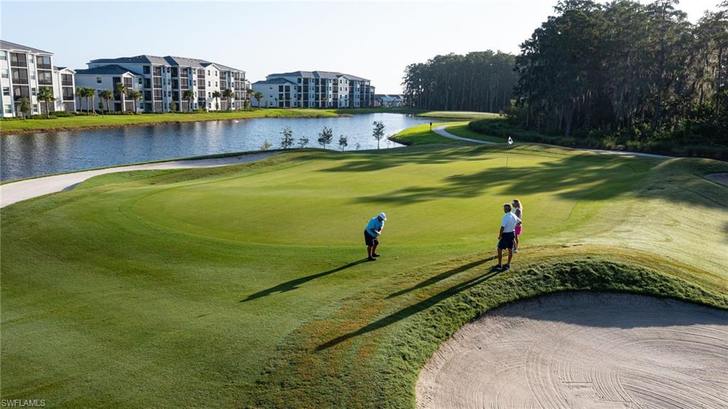 Lakeside golf course with a sand bunker, manicured green, and surrounding residential buildings