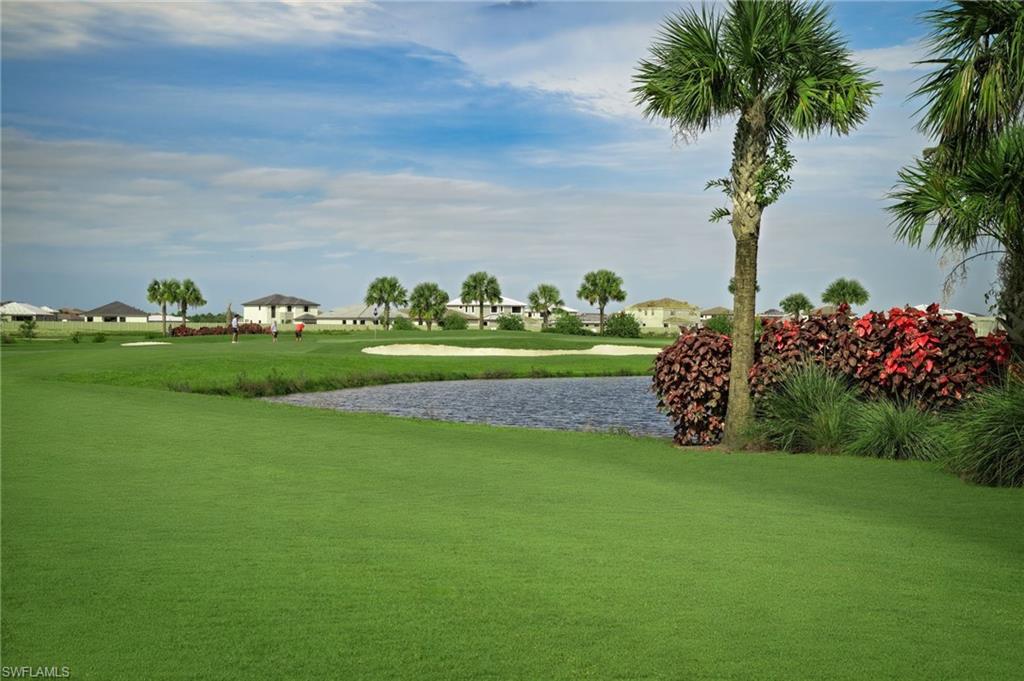 Expansive golf course setting featuring a water hazard, sand trap, and mature palm trees