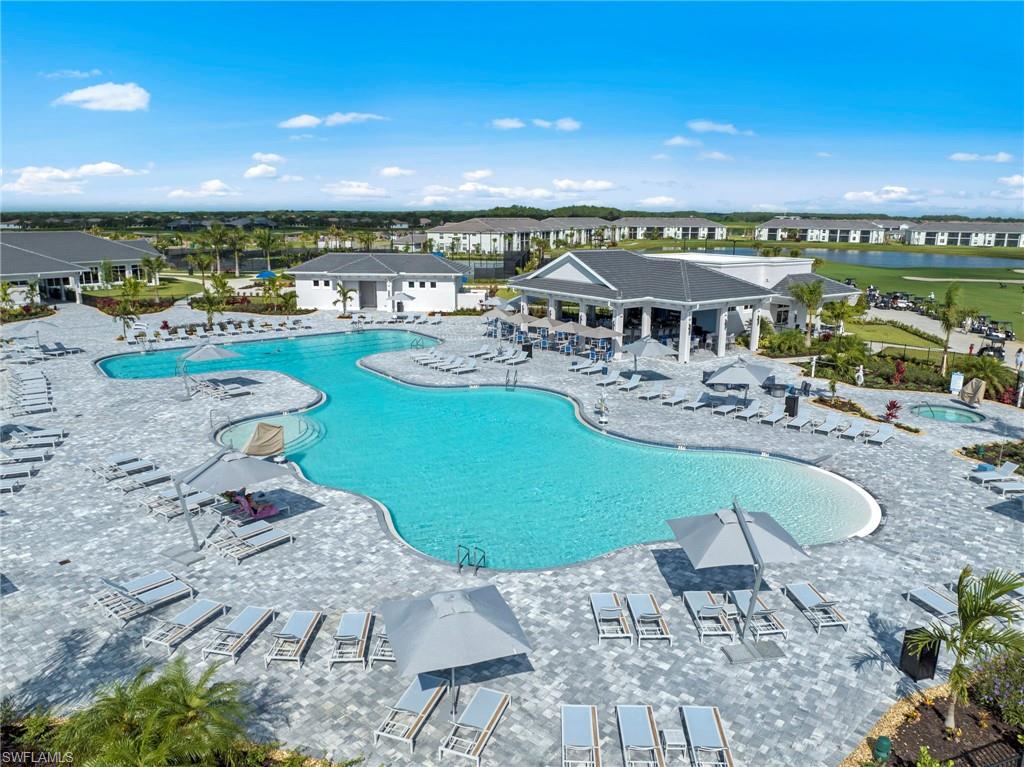 Expansive pool area featuring a large, freeform swimming pool, integrated spa, and extensive paver decking