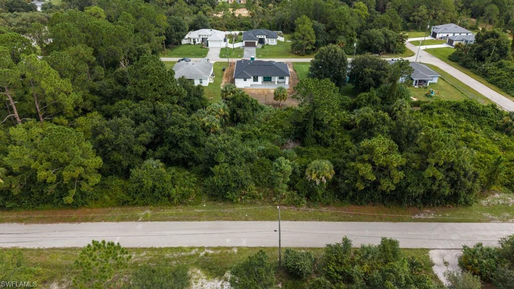 Aerial view showcasing multiple residences nestled within mature tree canopy, with a paved road frontage and verdant landscaping throughout the neighborhood