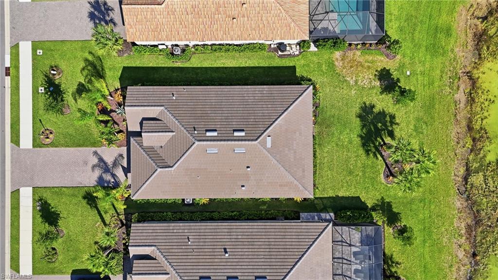 Aerial view showcasing two residences with architectural rooflines featuring multiple peaks and dormers, dark shingle finishes, and integrated guttering