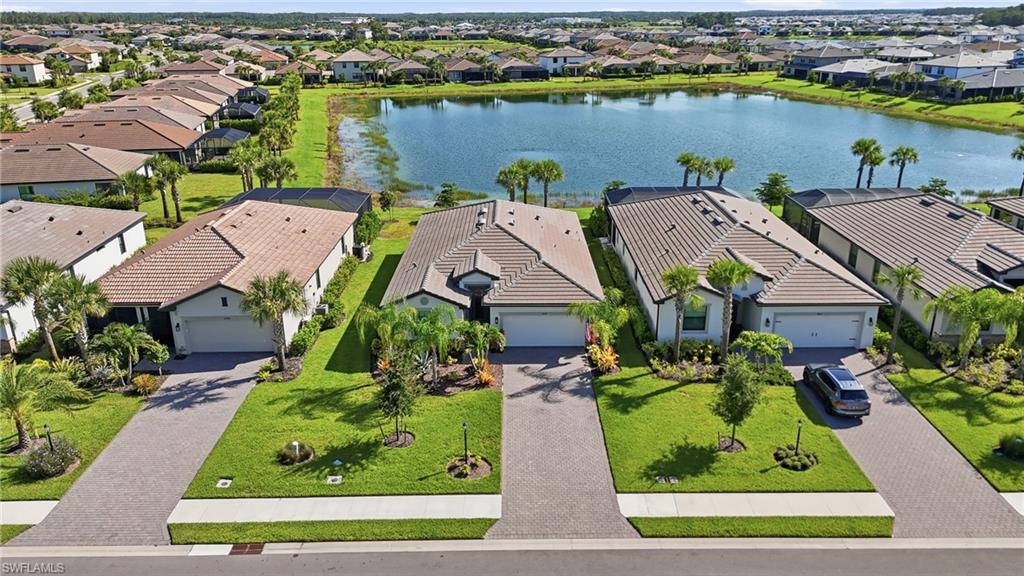 Contemporary home with a tile roof, paver driveway, attached garage, and mature landscaping