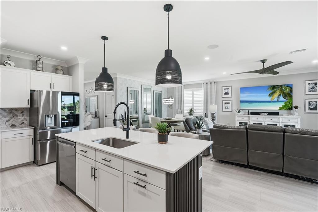 Open-concept living area with light wood-finish flooring, white cabinetry, and stainless steel appliances