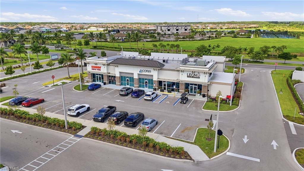 Commercial building with multiple storefronts, ample paved parking, and visible signage