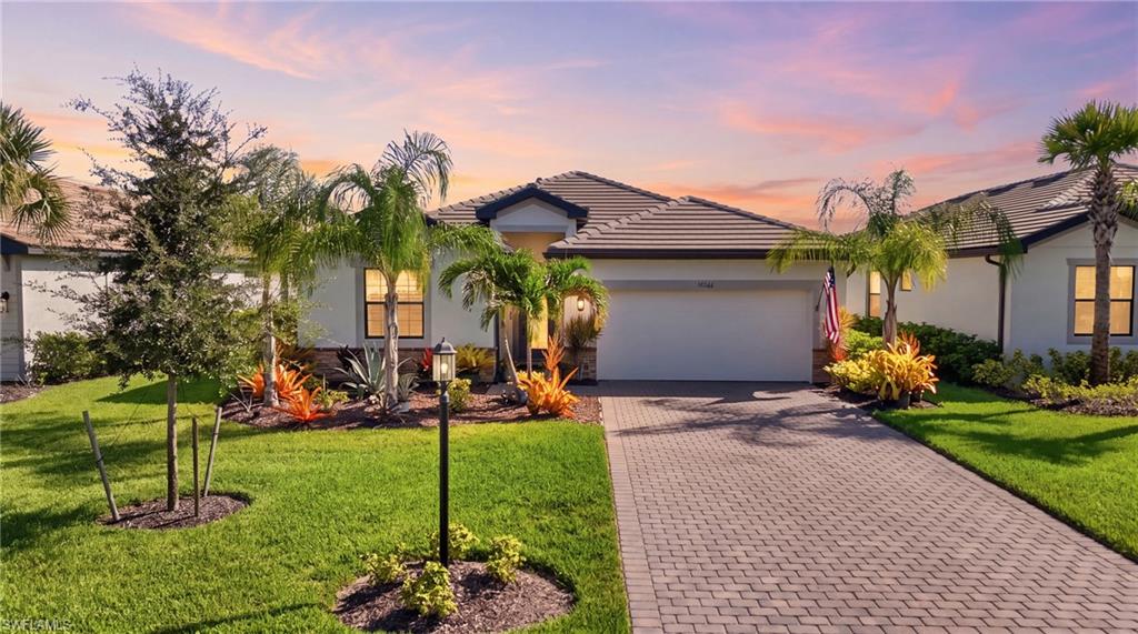 Modern residence showcasing a manicured front landscape with mature palm trees, vibrant tropical plantings, and decorative accent lighting
