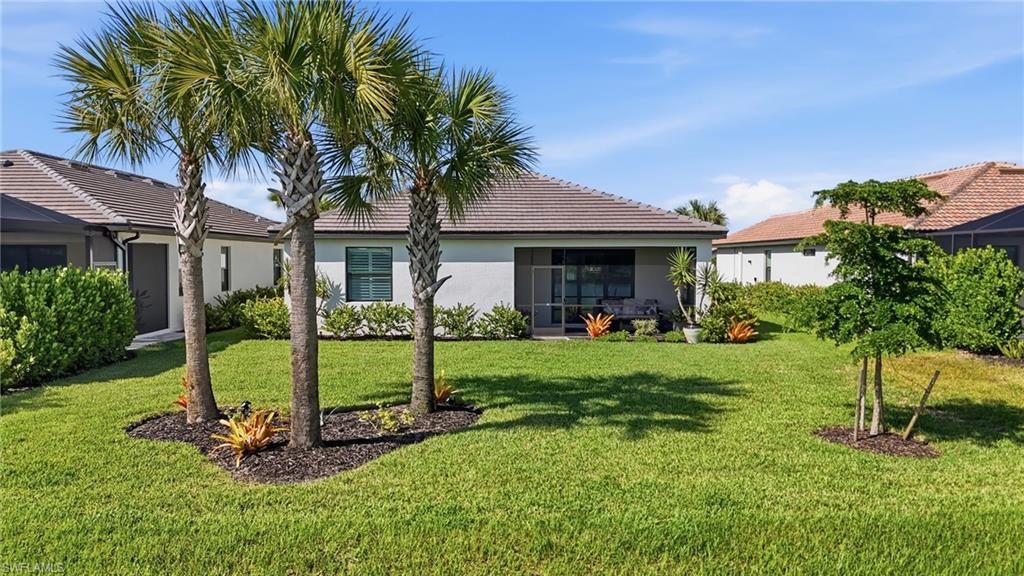 Mature landscaping anchors this single-story residence, featuring established palm trees and lush lawn with defined planting beds