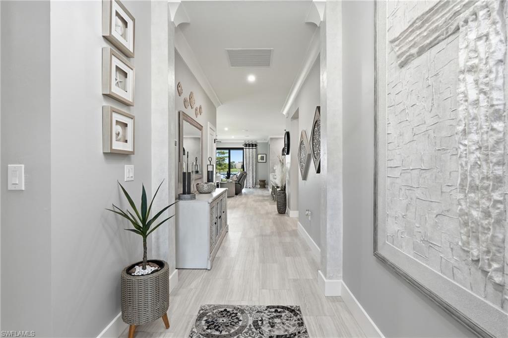 Bright hallway showcasing light wood-finish flooring, white shiplap accent wall, recessed ceiling lighting, and framed wall art