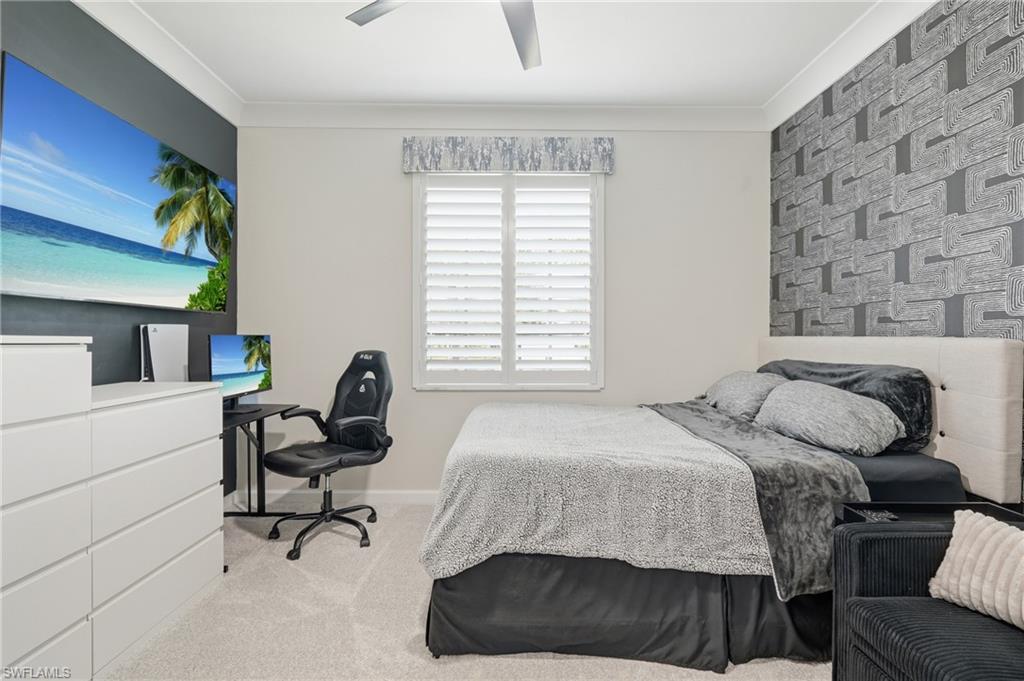 Modern bedroom featuring a geometric brick accent wall, white plantation shutters, carpeted flooring, recessed ceiling lighting, and white built-in cabinetry with integrated storage drawers