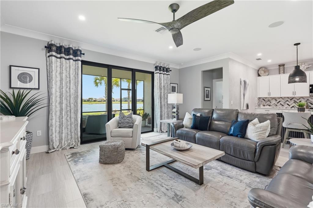 Sophisticated open-concept living space featuring a gray upholstered sectional, light wood-finish flooring, and a neutral area rug anchoring the seating arrangement