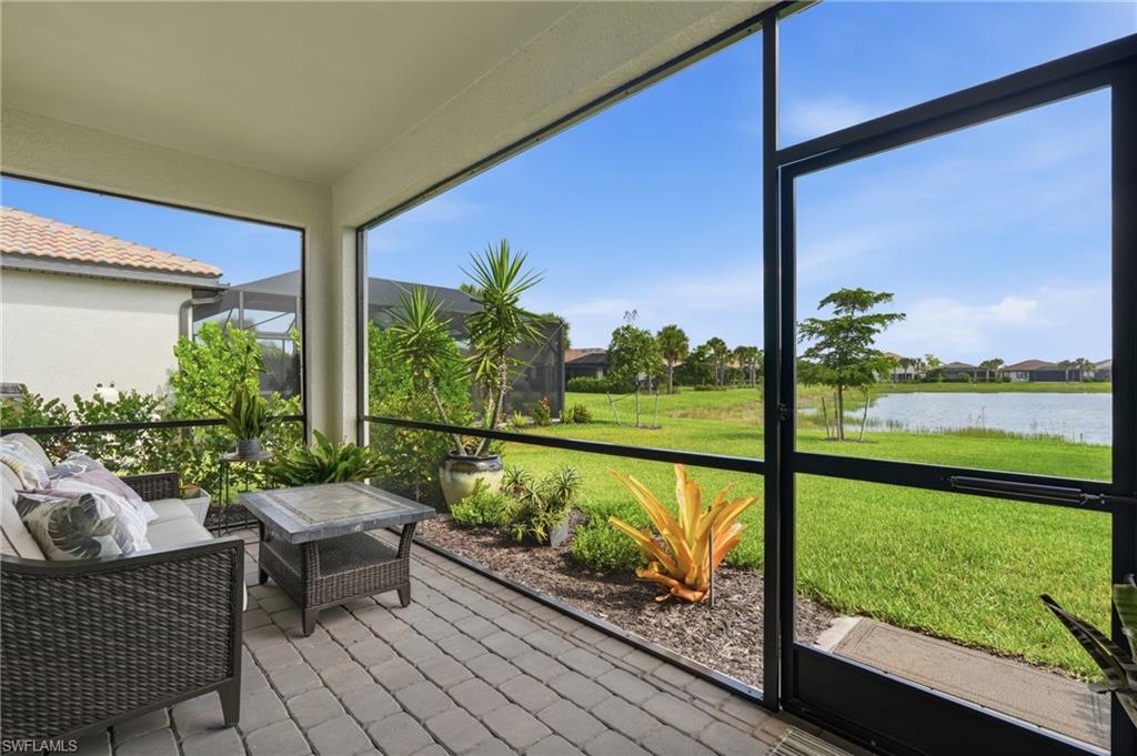 Screened lanai featuring paver flooring, overhead lighting, and landscaped beds