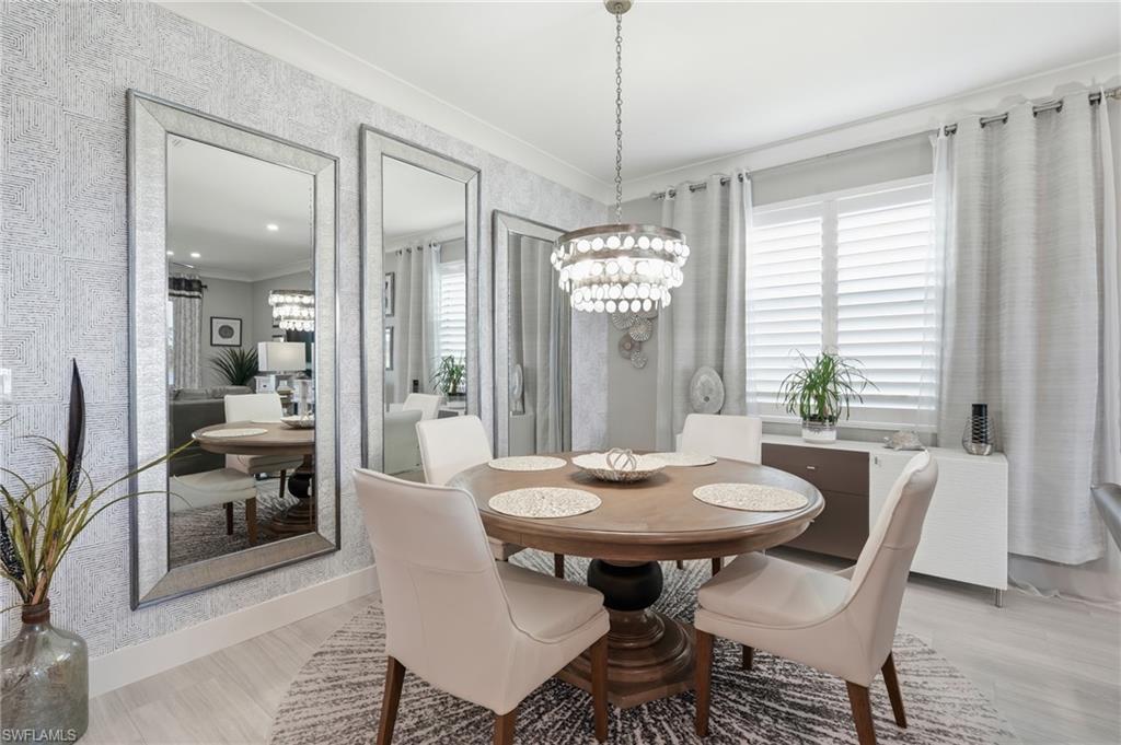 Elegant dining room featuring a round pedestal table, four upholstered chairs, and a crystal chandelier suspended from a coffered ceiling