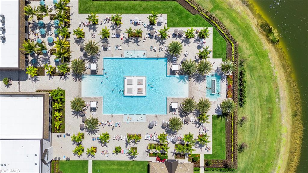 Resort-style resort pool with turquoise waters and zero-entry design, surrounded by expansive sun deck with mature palm trees and manicured lawn
