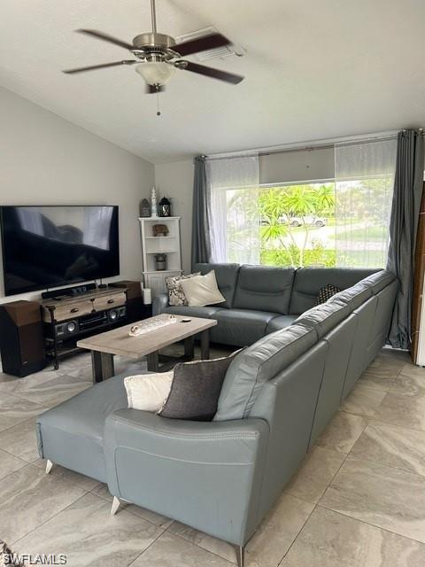 Vaulted ceilings, a ceiling fan with integrated lighting, large windows, wood-finish media console, and tile flooring