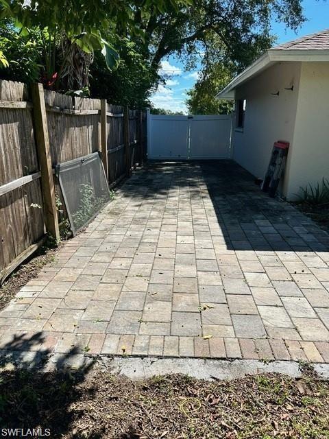 Paved outdoor area featuring a wood fence, privacy gate, and stucco exterior