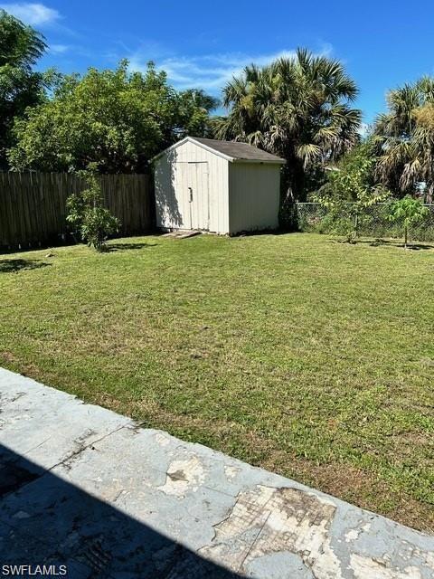 Expansive grassy yard with a wooden storage shed and perimeter fencing