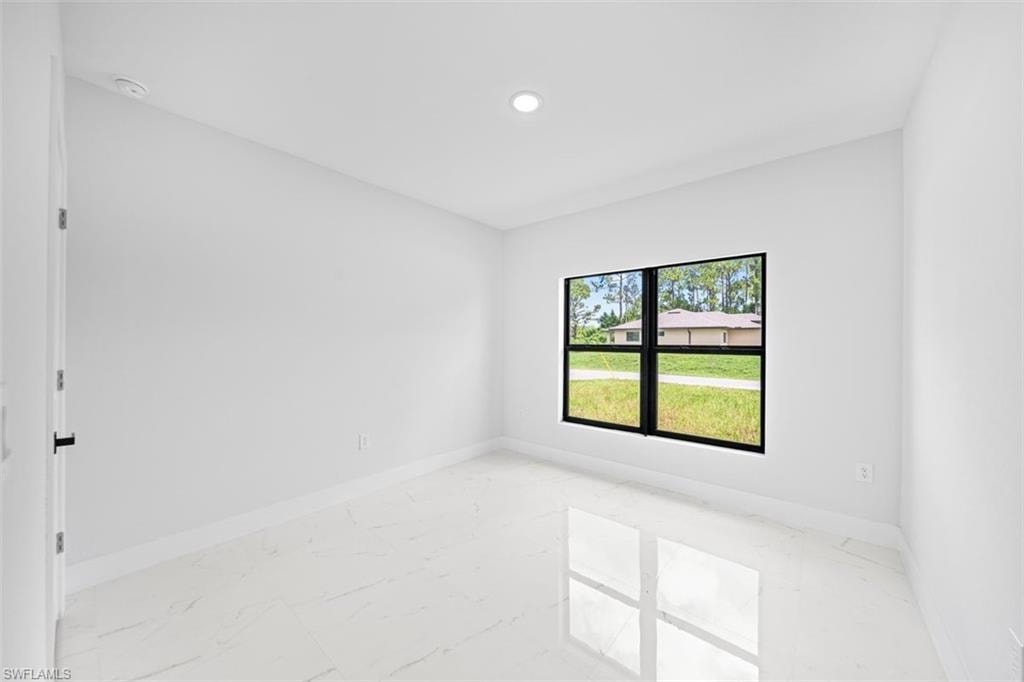 Recessed ceiling lighting, a large window with black framing, white walls, and light-colored tile flooring