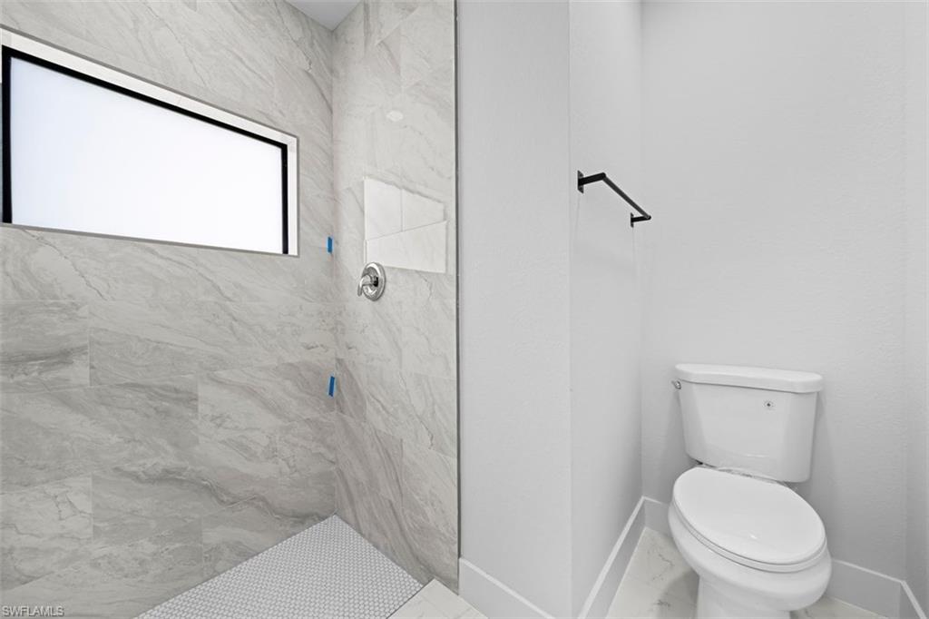 Tiled shower with a horizontal window, chrome fixtures, and a glass partition