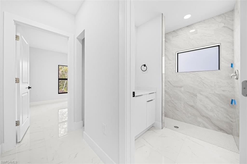 Contemporary full bathroom featuring a walk-in shower with tile surround, built-in window, and a single vanity with stone countertop