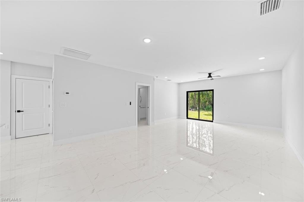 Spacious open-concept room featuring polished light-finish flooring throughout, recessed ceiling lighting, and abundant natural light from a large fixed window