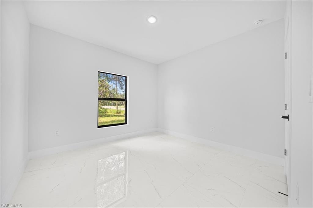 Recessed ceiling lighting, a single window with black trim, and polished tile flooring