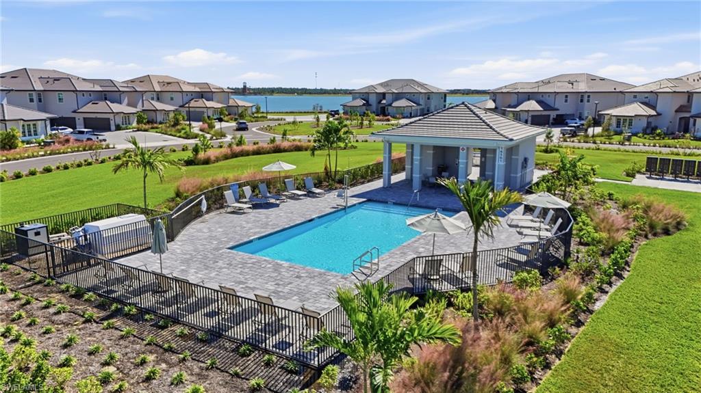 Rectangular inground pool with paver decking, fenced perimeter, and a detached covered cabana