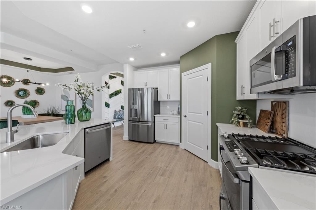 Kitchen featuring stainless steel appliances, wood-finish flooring, white cabinetry, recessed lighting, and white countertops