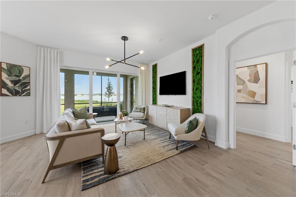 Spacious living area featuring wood-finish flooring, a contemporary chandelier, and sliding glass doors