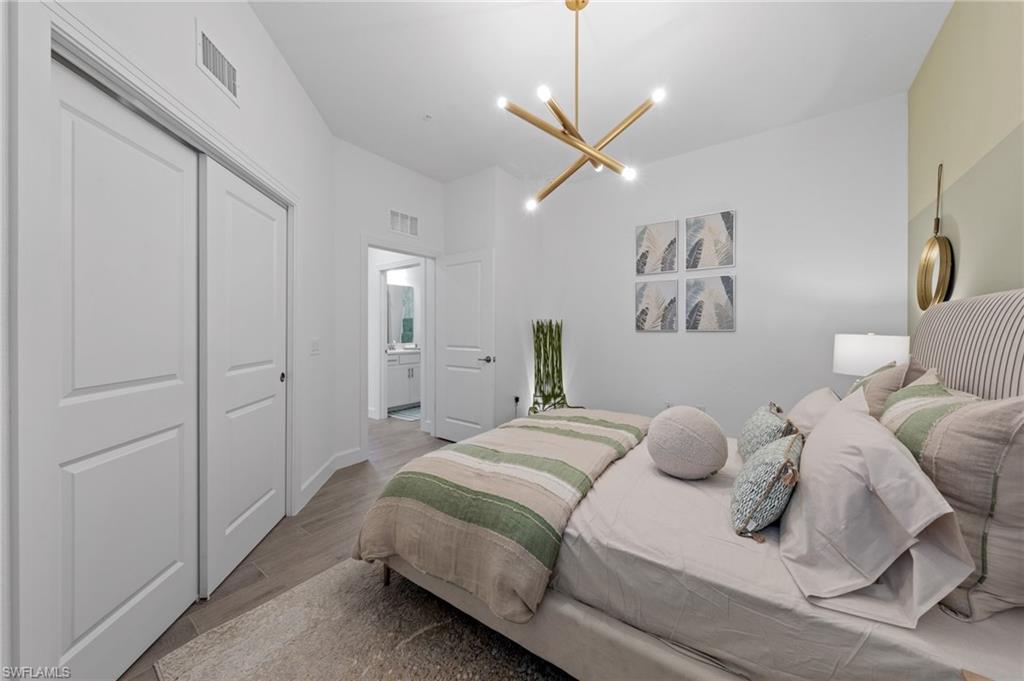 Wood-finish flooring, built-in closet with sliding doors, contemporary ceiling light fixture, and a solid core door
