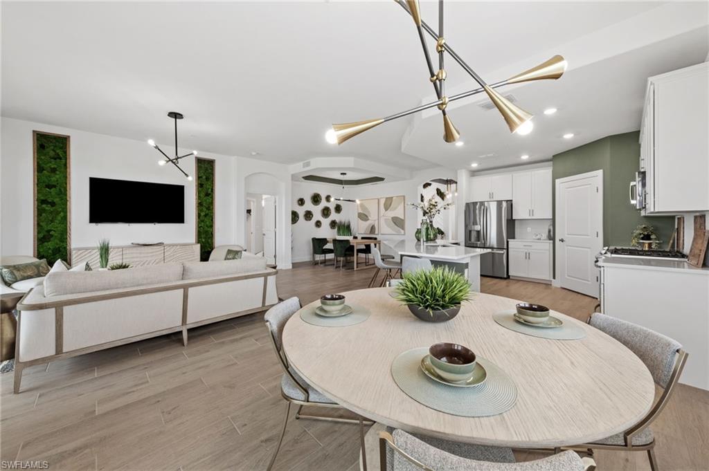 Open-concept living area with wood-finish flooring, recessed lighting, and modern chandeliers