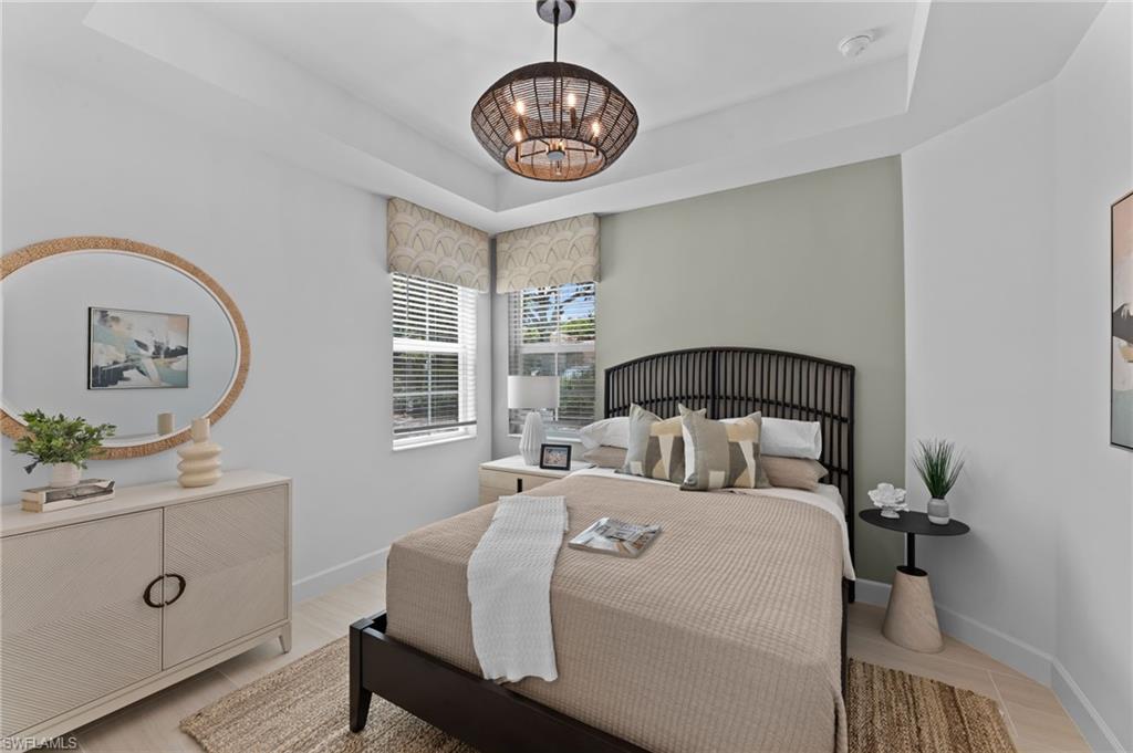 Tray ceiling with a central woven chandelier, dual windows featuring blinds and valances, and wood-finish flooring