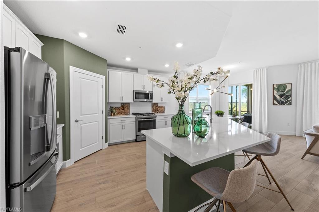Modern kitchen featuring white cabinetry, stainless steel appliances, a center island with a white countertop, wood-finish flooring, and recessed lighting