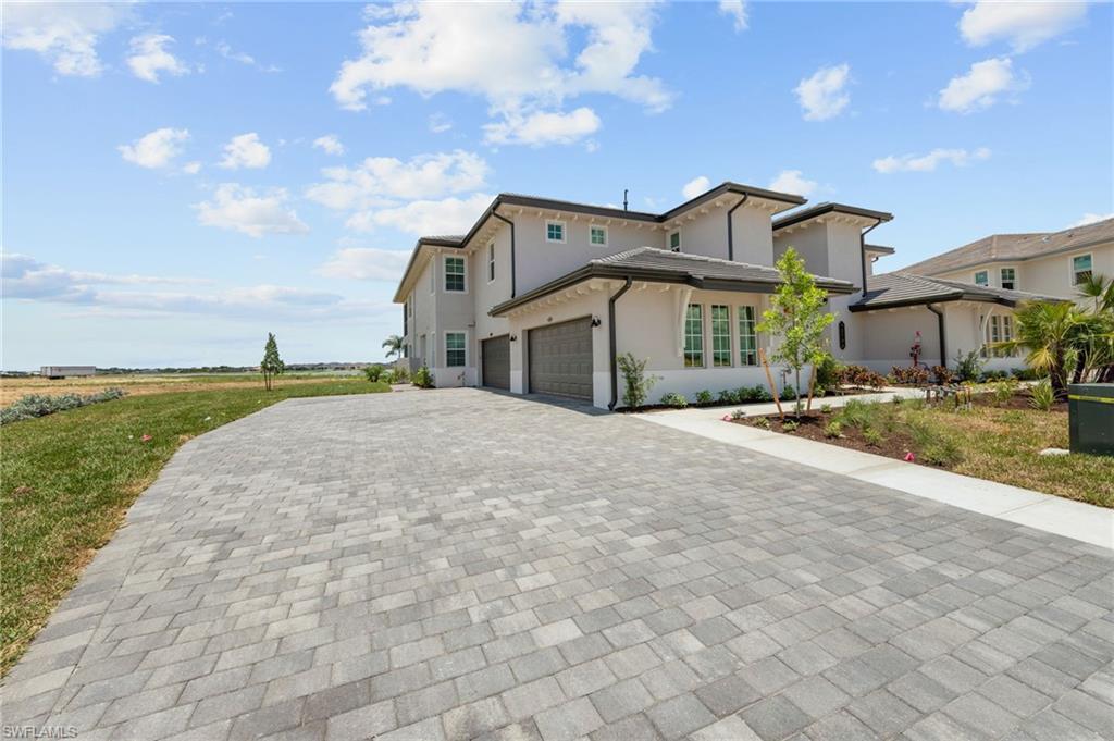 Contemporary exterior with a multi-car paver driveway, two-car garage, established landscaping, and stucco finish