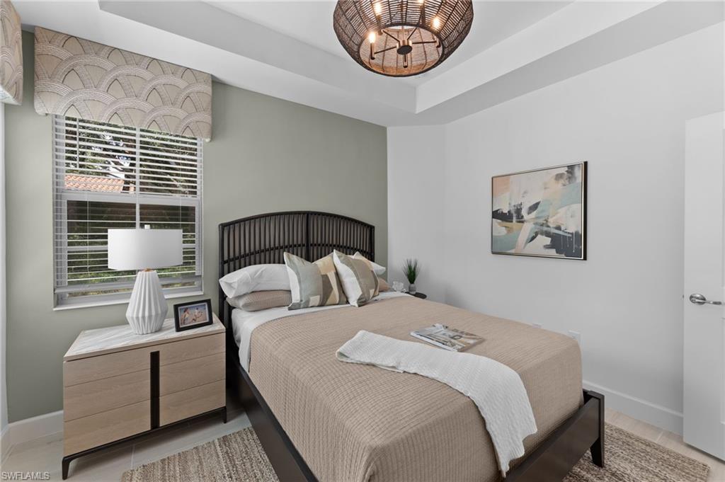 Tray ceiling with a dark woven chandelier, single window with blinds and valance, light wood-finish nightstand with a stone top, and light flooring