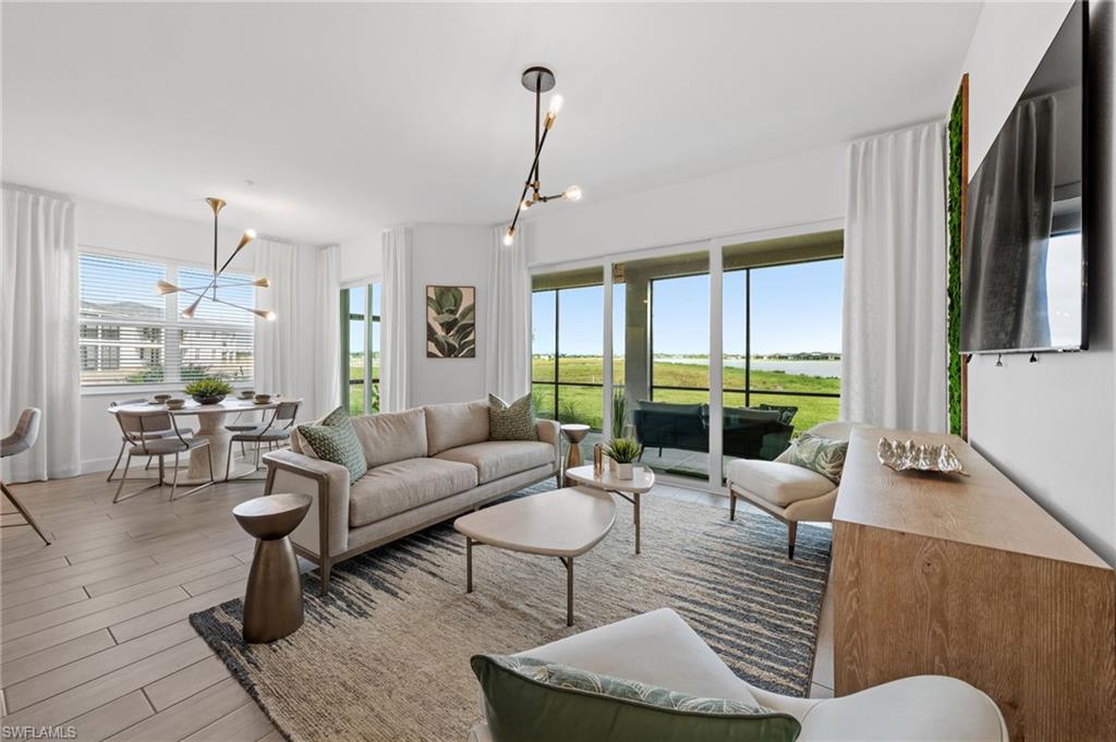 Open-concept living space featuring wood-finish flooring, a wall of sliding glass doors leading to a screened patio, and a dedicated dining area with a modern chandelier