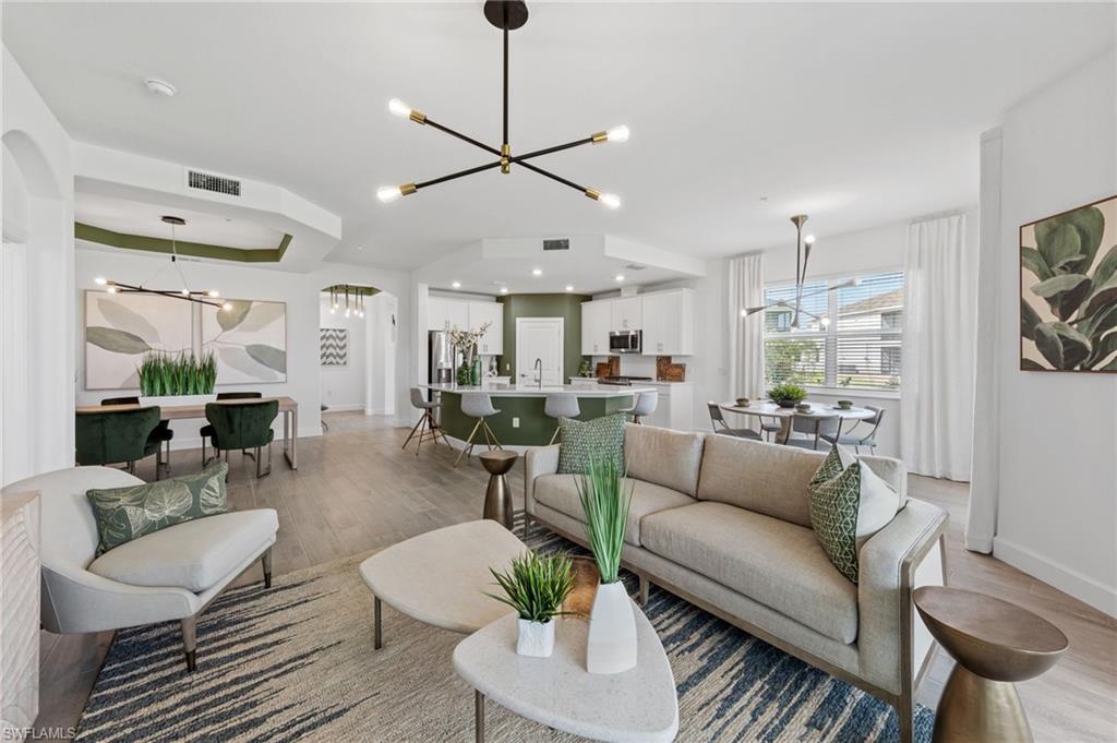 Open-concept living area with wood-finish flooring, a contemporary chandelier, and recessed lighting