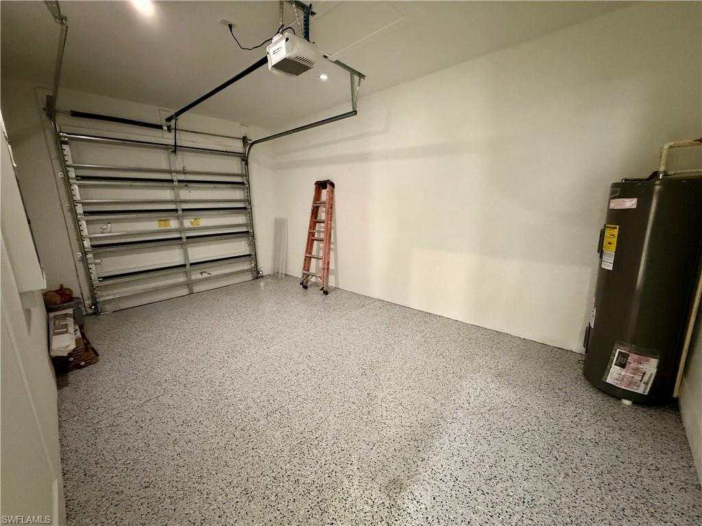 Garage space featuring a speckled epoxy floor, white painted walls, and an overhead garage door opener
