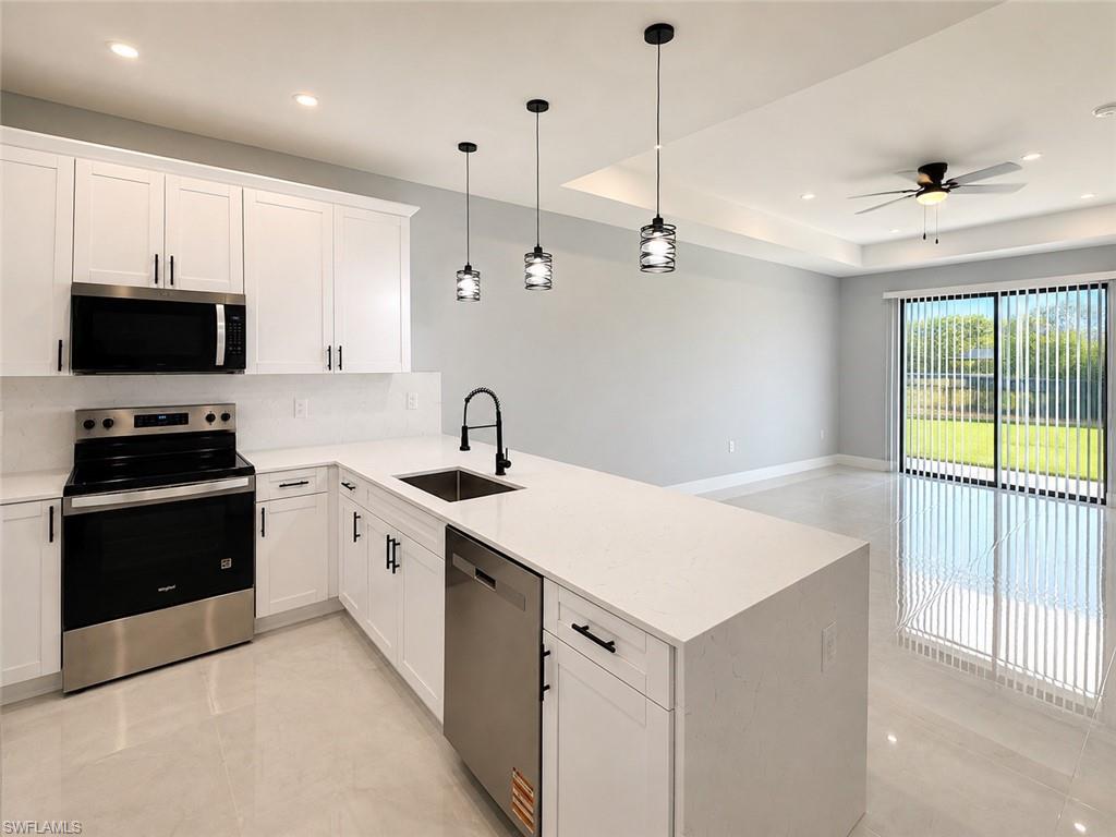 Kitchen featuring white shaker cabinetry, stainless steel appliances, a white solid surface countertop, and a wood-finish island with pendant lighting