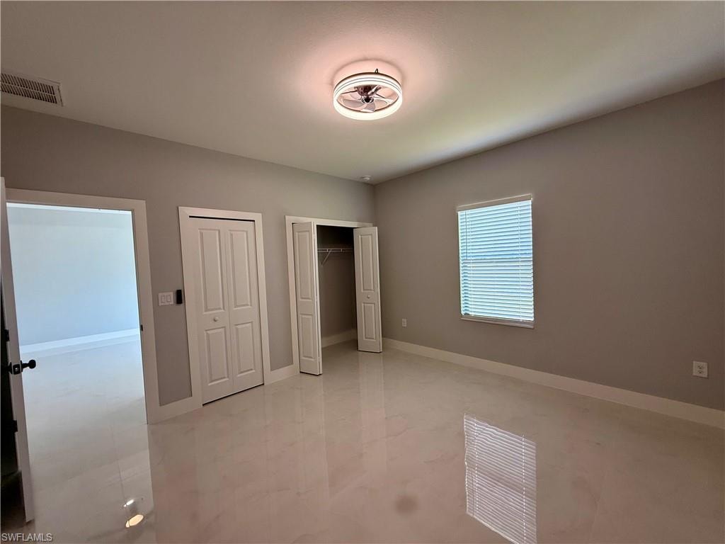 Spacious room featuring glossy tile flooring, neutral wall paint, and a built-in closet with bi-fold doors