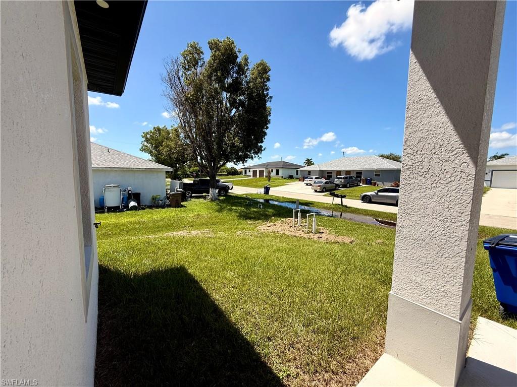 Manicured lawn with visible irrigation components, bordered by a textured stucco exterior