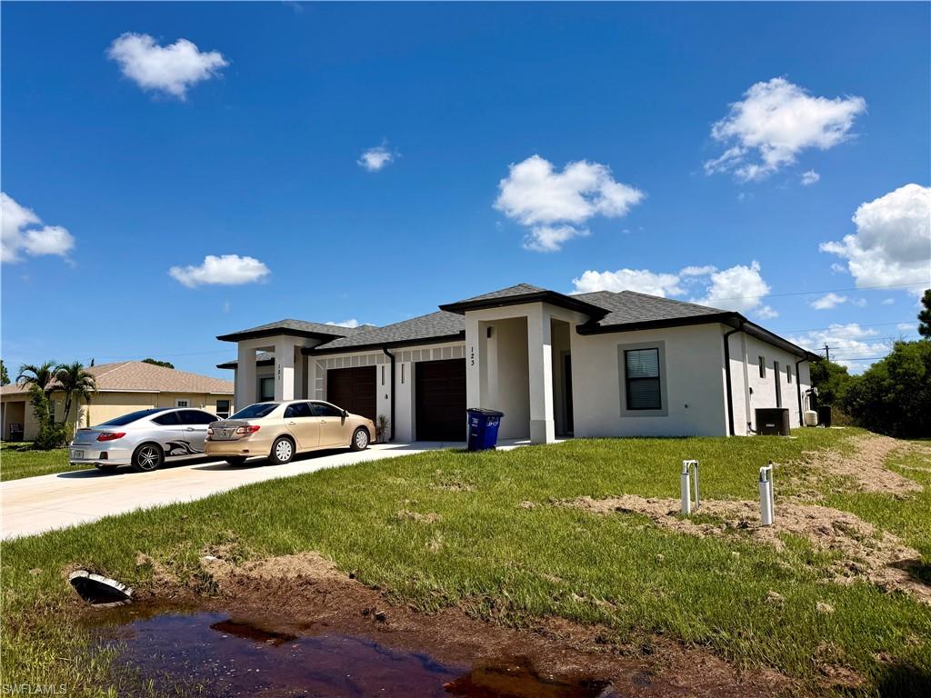 Contemporary stucco exterior with dark trim, two-car garage with wood-finish doors, and a paved driveway