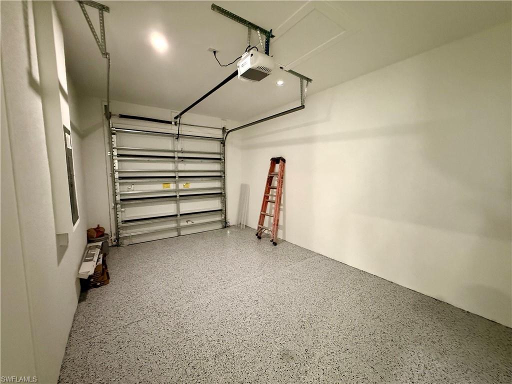 Garage with a speckled epoxy floor, white walls, recessed ceiling lighting, and an overhead garage door