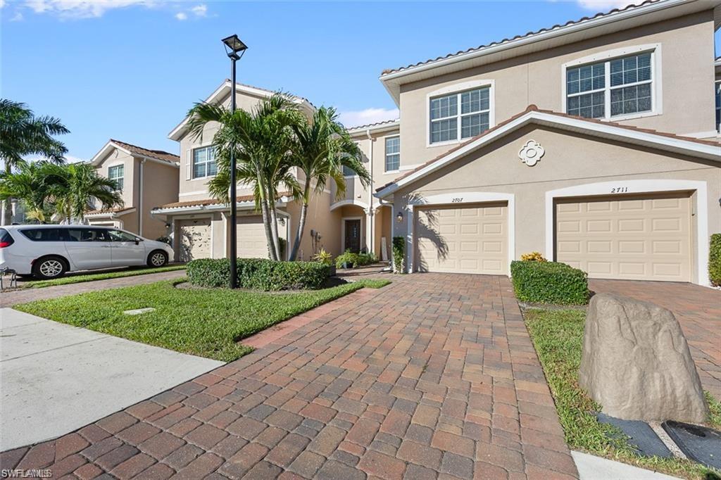 Stucco exterior with multiple windows, two-car garage, and a paver driveway
