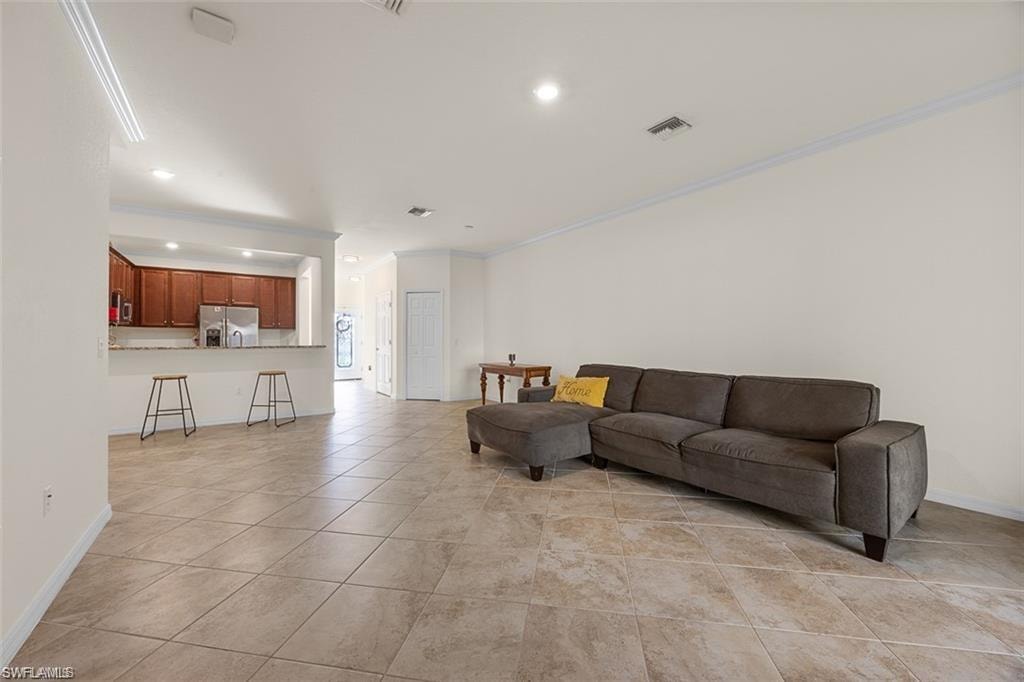 Open-concept living area with large format tile flooring, crown molding, and recessed lighting